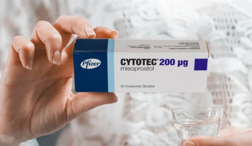 Mujer con una caja de pastillas Cytotec para abortar y un vaso de agua